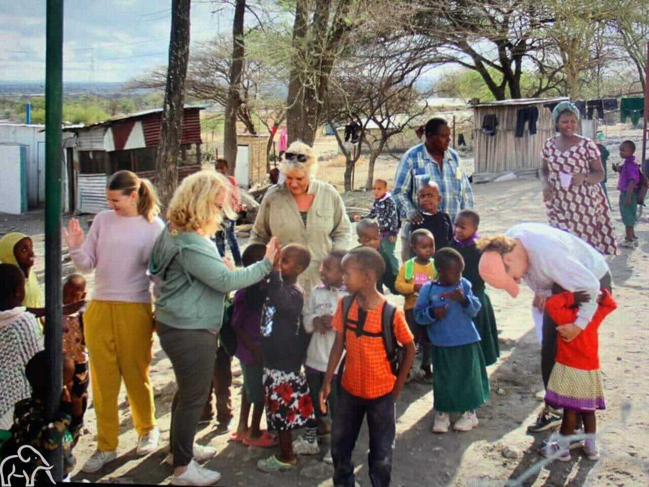 Culturele activiteit rondreis Tanzania. Gasten en lokale kinderen maken plezier en praten met elkaar