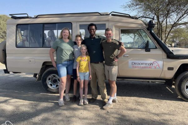 Reizigers met hun gids bij de safariauto